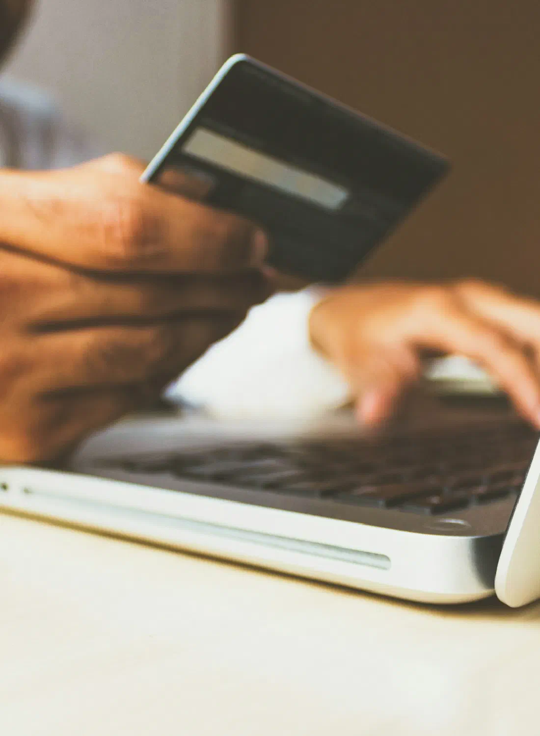 Paying online with a bank card at a laptop — the checkout step your gateway owns